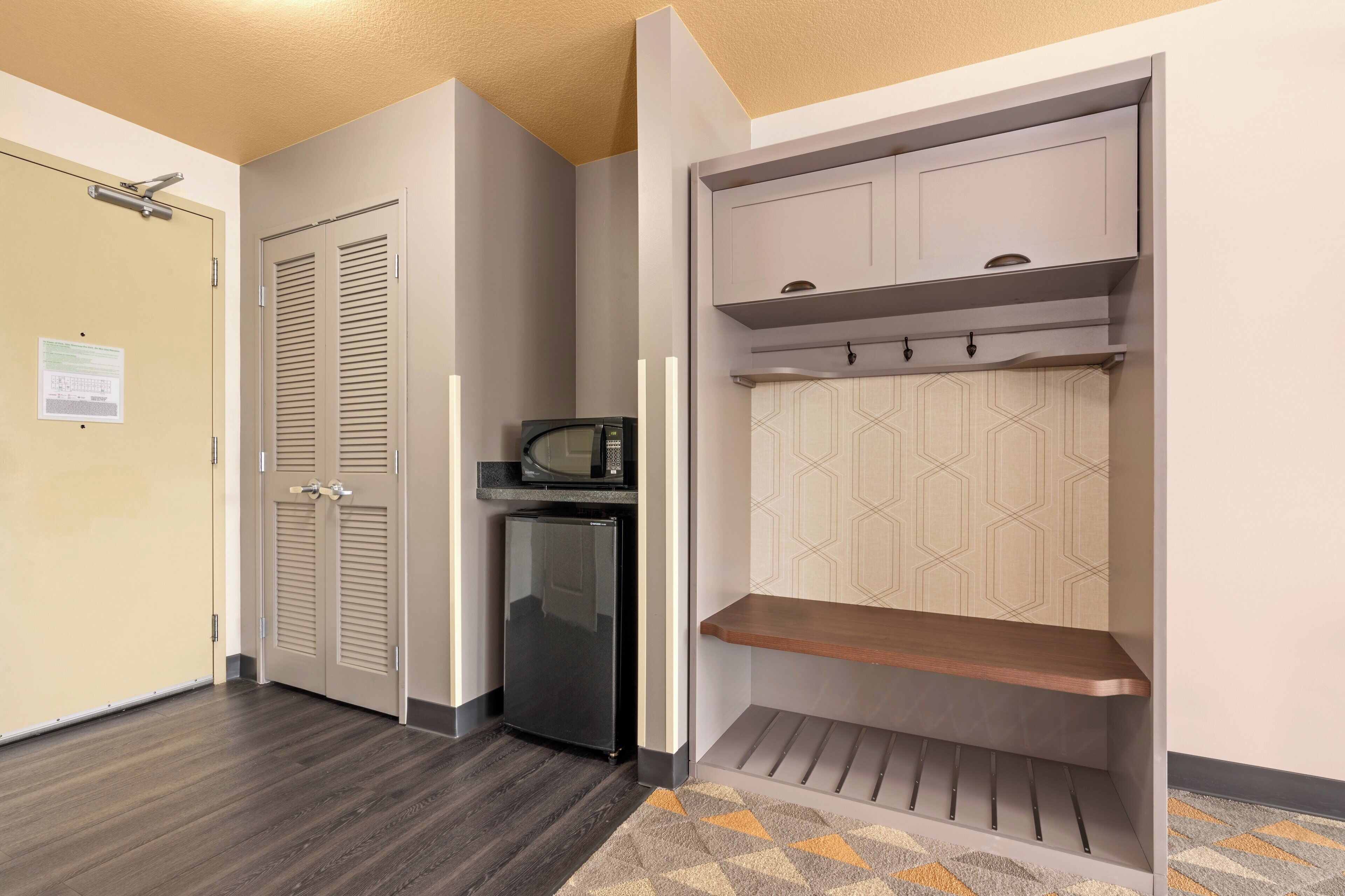 A hallway with a wardrobe, a microwave, and a refrigerator.