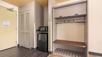 A hallway with a wardrobe, a microwave, and a refrigerator.