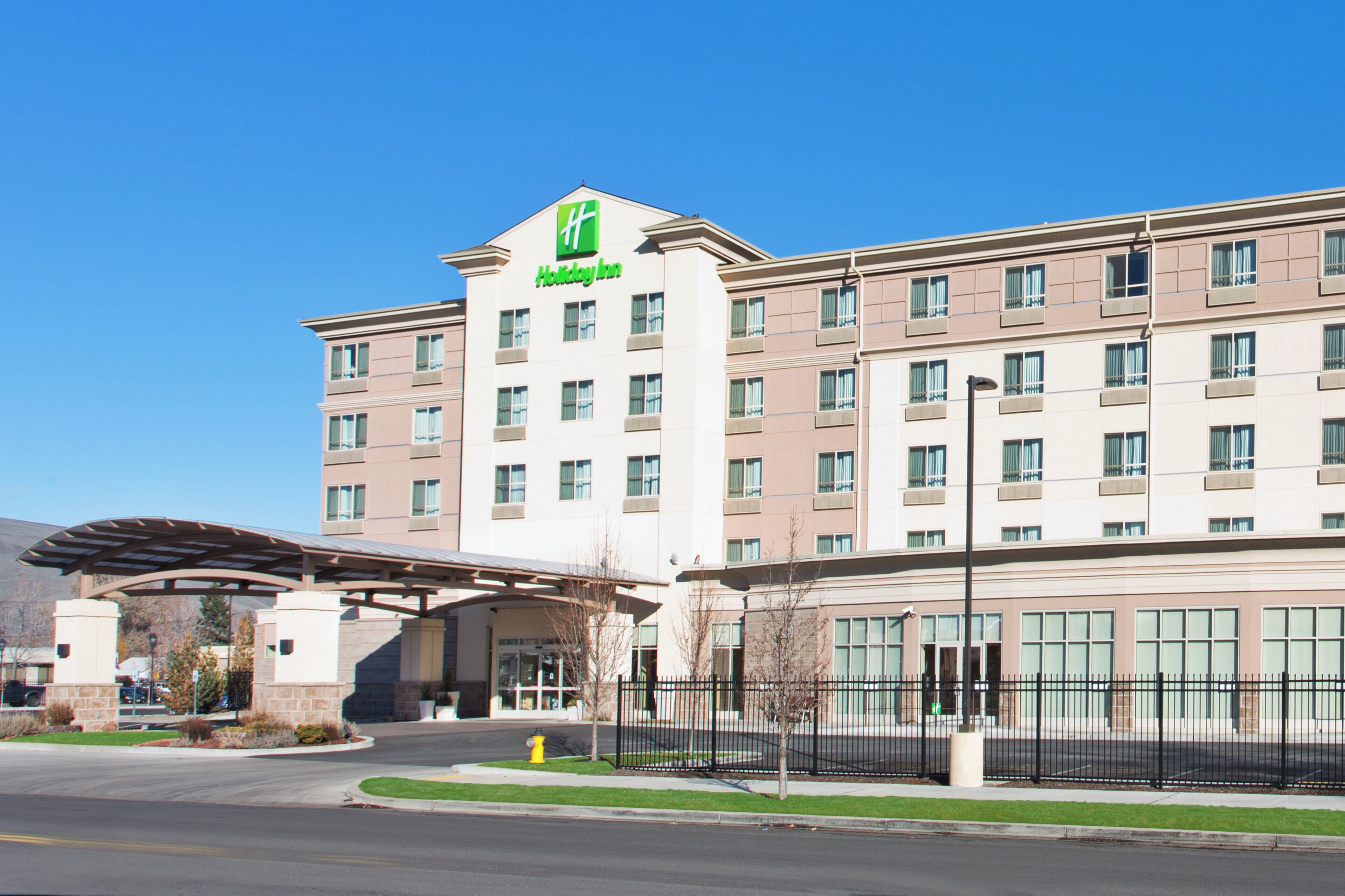 A Holiday Inn hotel with a covered entrance, multiple floors, and a clear sky.