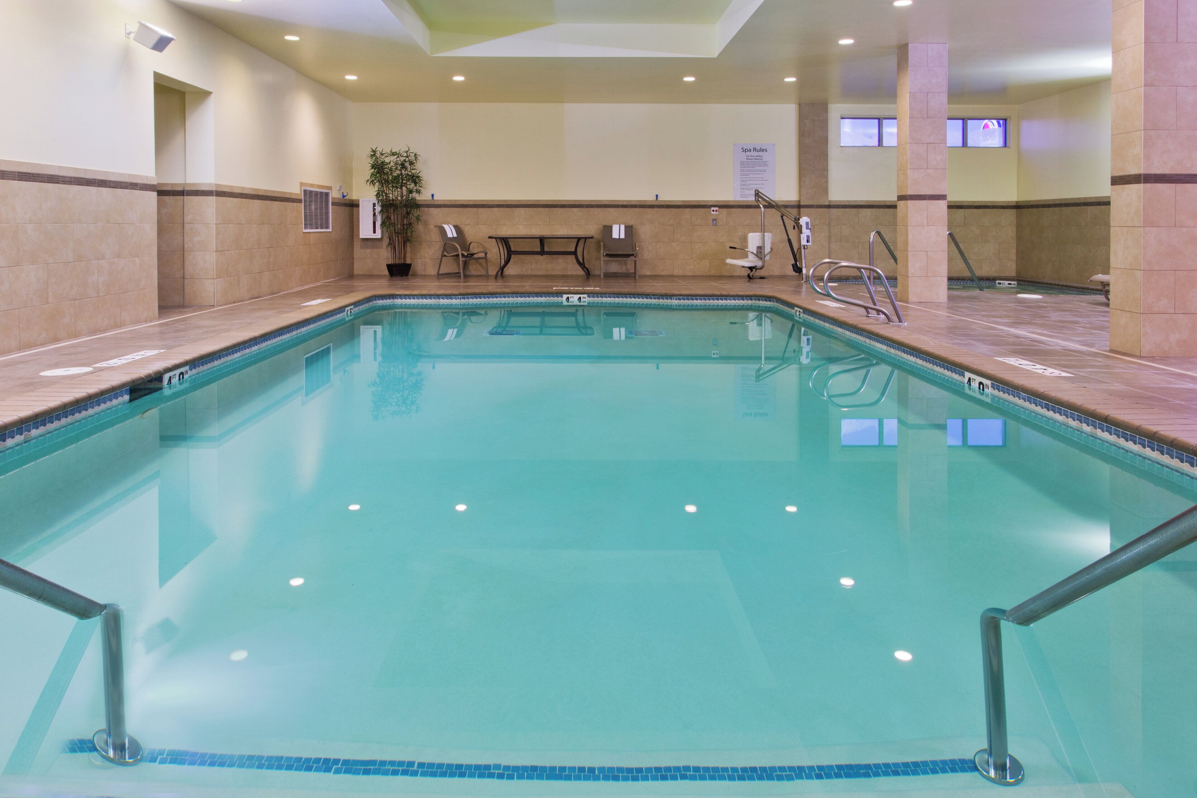 A large indoor swimming pool with clear water, surrounded by tiled walls and a bench.