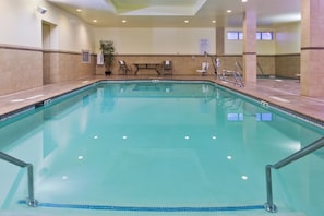 A large indoor swimming pool with clear water, surrounded by tiled walls and a bench.