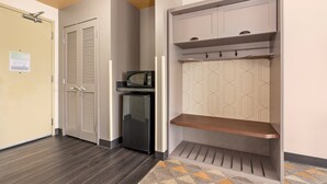 A hallway with a wooden floor, a microwave, a refrigerator, and a wardrobe with a hanging shelf. - Holiday Inn Yakima by IHG (Yakima)