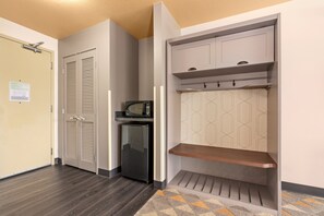 A hallway with a wooden floor, a microwave, a refrigerator, and a wardrobe with a hanging shelf. - Holiday Inn Yakima by IHG (Yakima)
