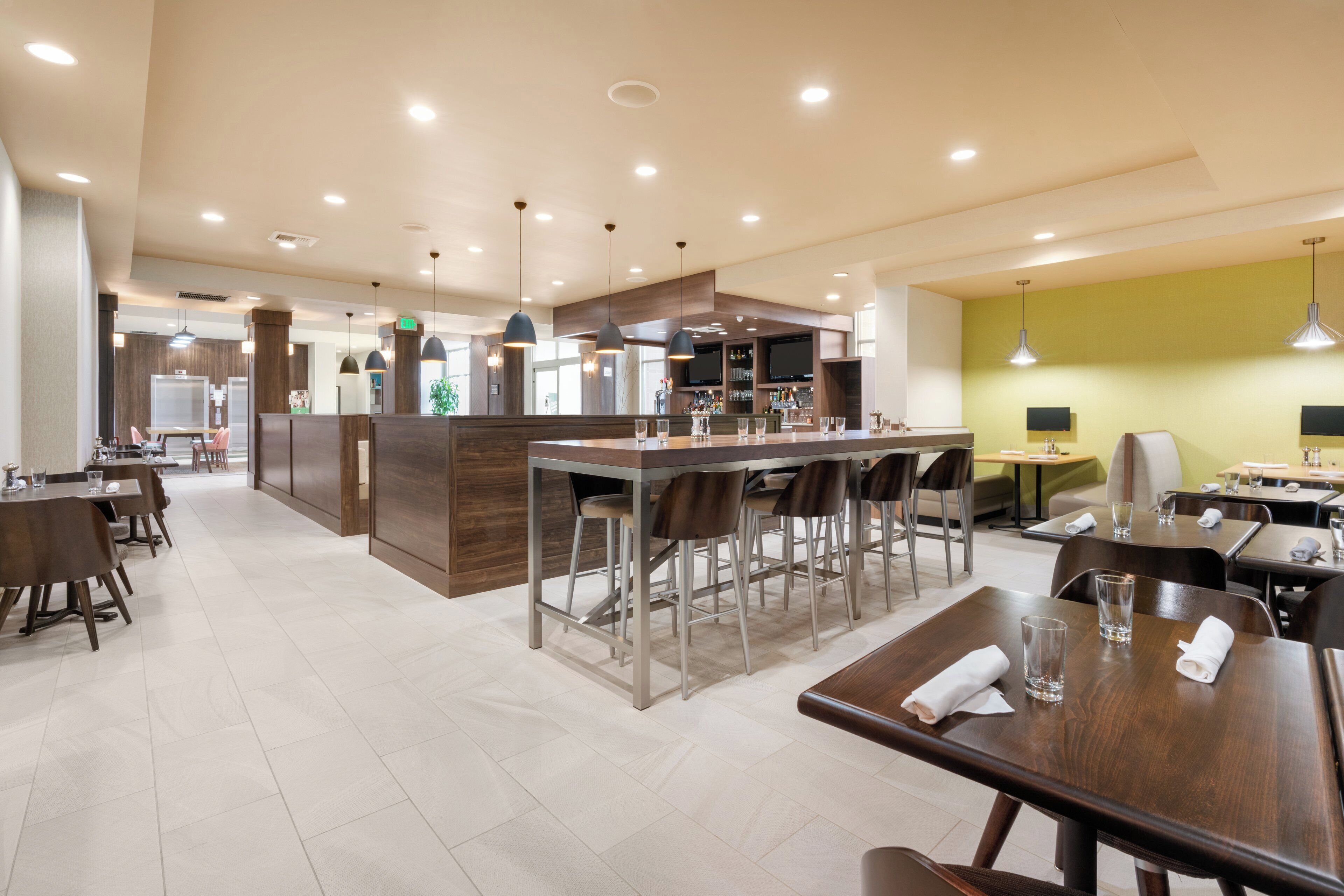 Un restaurant moderne doté d’un bar, de hauts plafonds et d’un éclairage abondant.