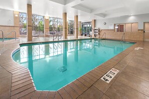 An indoor swimming pool with clear water, tiled floor, and a lifeguard chair.