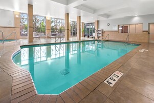 Una piscina interior con agua cristalina, suelo de baldosas y una silla de socorrista.