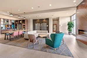 A modern lobby with a seating area, a kitchen, and a reception desk.