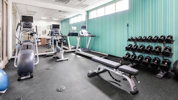 A gym with treadmills, elliptical machines, and a rack of dumbbells.