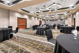 Un salón de conferencias con varias mesas, sillas y una alfombra estampada.