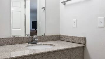 A bathroom with a granite countertop sink, a mirror, and a towel rack.