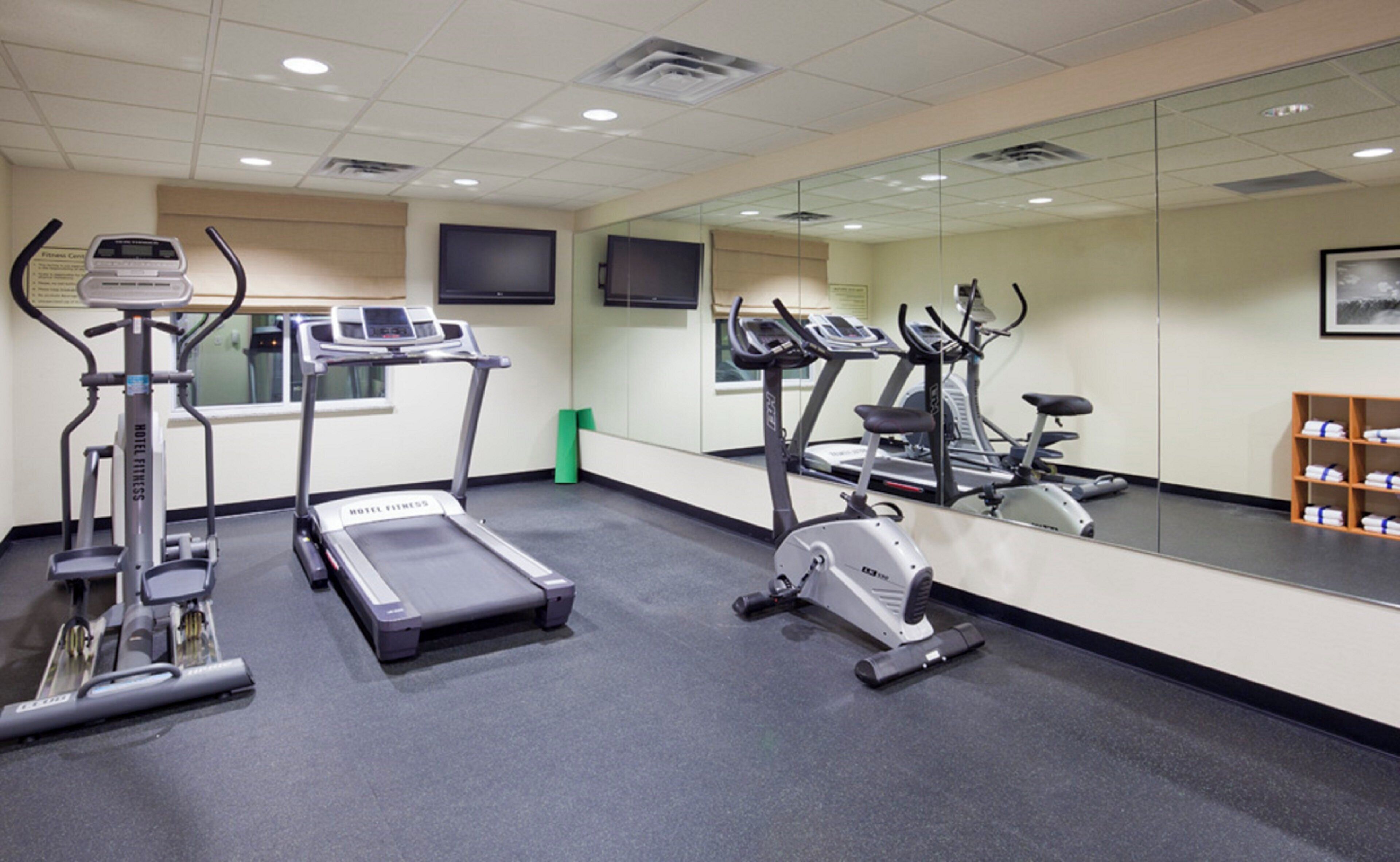 Gimnasio de hotel con cintas de correr, elíptica y bicicleta estática.