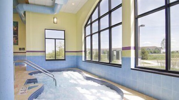 A spa area with a hot tub, large windows, and a view of the outdoors. - Holiday Inn Express Hotel & Suites Rogers by IHG (Rogers)