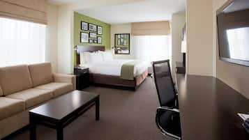 Quarto de hotel com cama, sofá, escrivaninha e televisão.