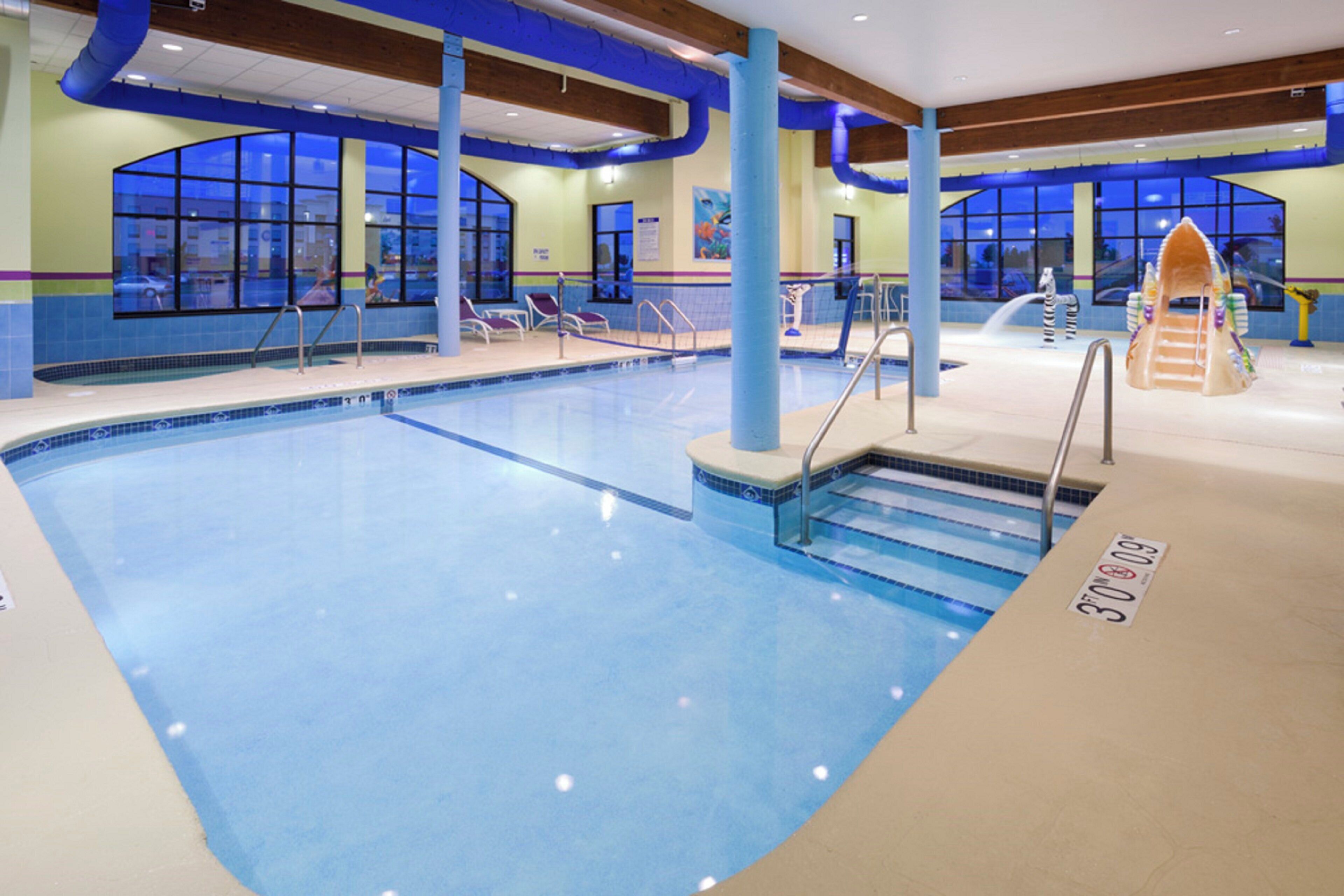 Ein Hallenbad mit klarem Wasser, Sprungbrett und Rettungsschwimmerstation.