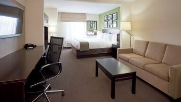 A hotel room with a bed, a desk with a chair, a sofa, and a TV.