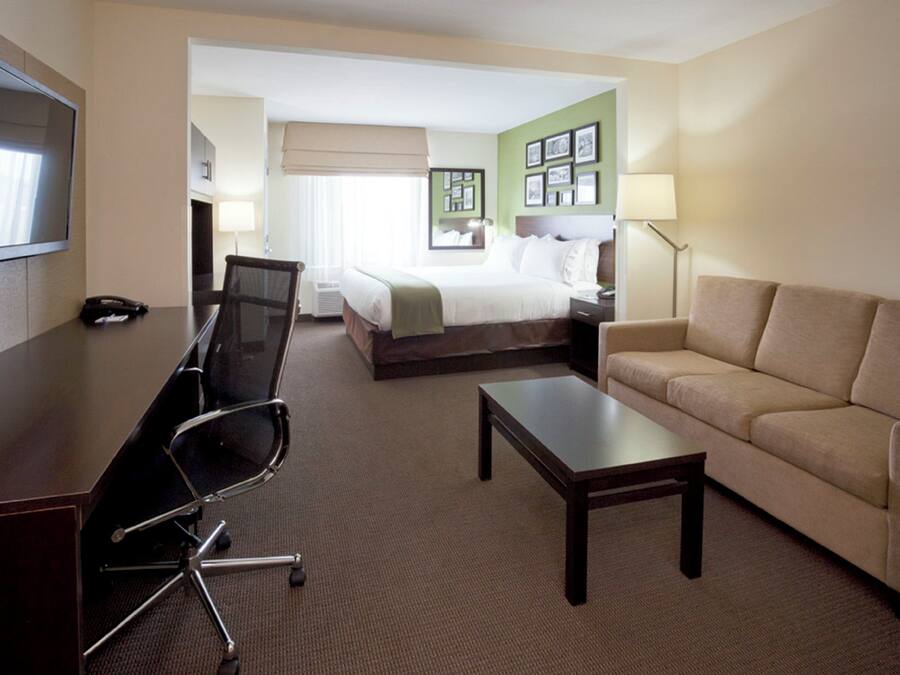 A hotel room with a bed, a desk with a chair, a sofa, and a TV.