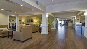 A spacious lobby with a high ceiling, wooden flooring, and a central seating area with sofas and tables. - Holiday Inn Express Hotel & Suites Rogers by IHG (Rogers)