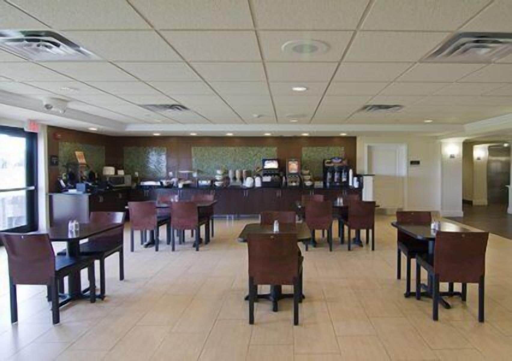 A hotel lobby with a reception desk, several tables and chairs, and a tiled floor.