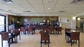 A hotel lobby with a reception desk, several tables and chairs, and a tiled floor.