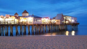 A wooden pier with multiple buildings, including a structure with a pointed roof and another with a flat roof. - Moby Dick Motel (Old Orchard Beach)