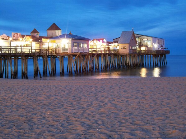 A wooden pier with multiple buildings, including a structure with a pointed roof and another with a flat roof.