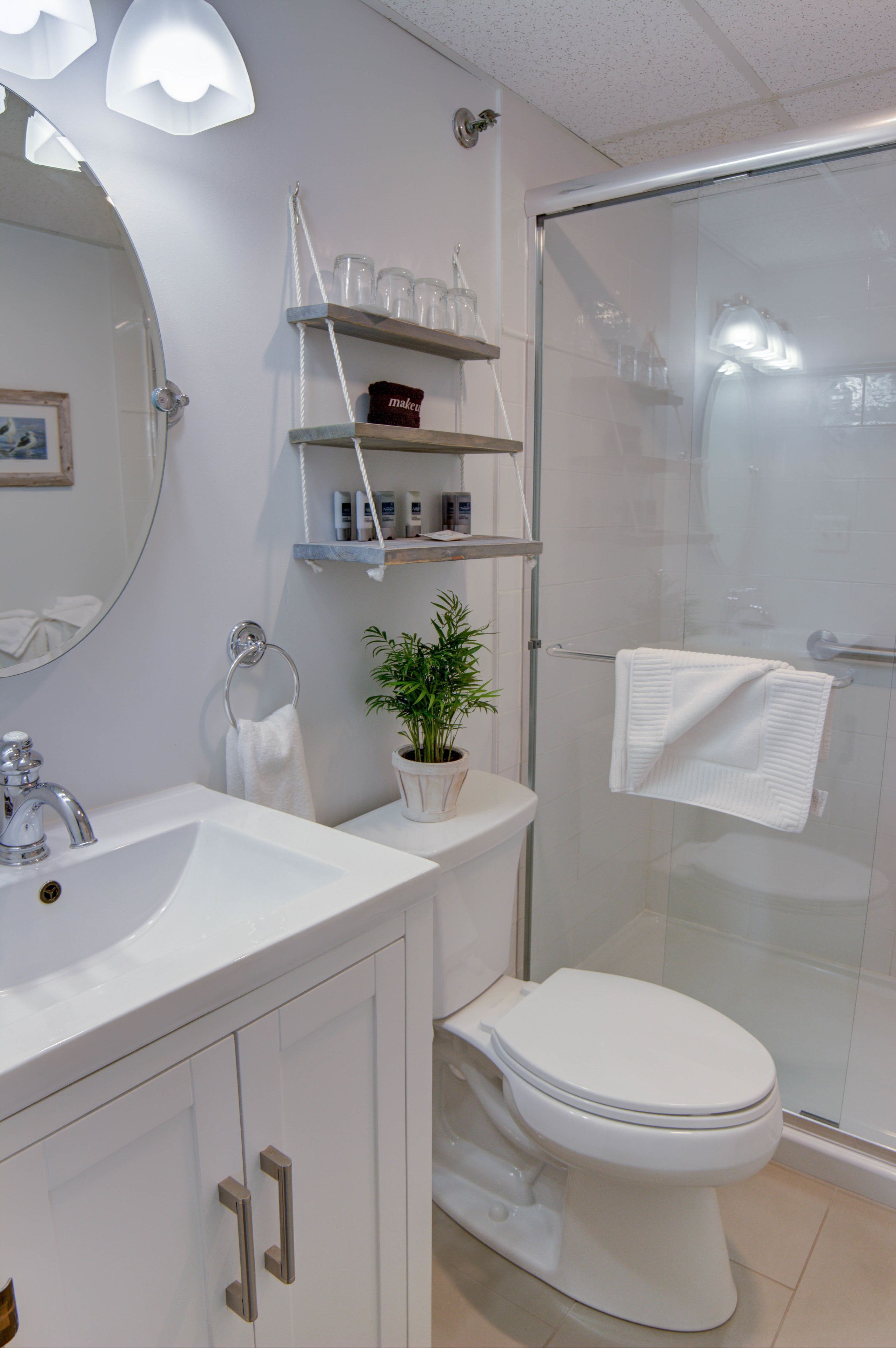 A modern bathroom with a white sink, a toilet, a glass shower enclosure, and a mirror with a ring light.