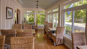 A sunlit room with wicker furniture, large windows, and ceiling fans. - Nonantum Resort (Kennebunkport)
