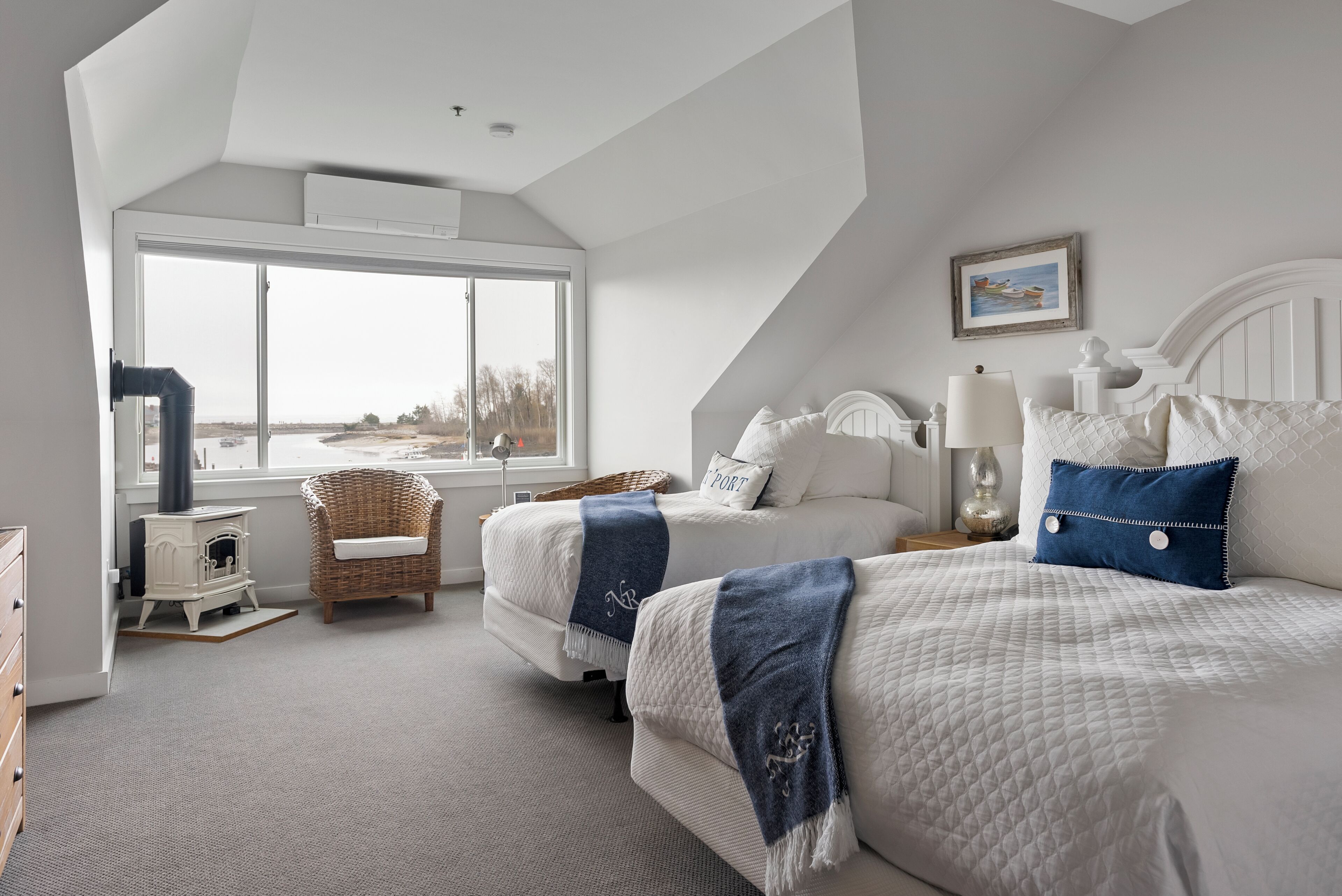 A bedroom with two beds, a window, a fireplace, and a view of the outdoors.