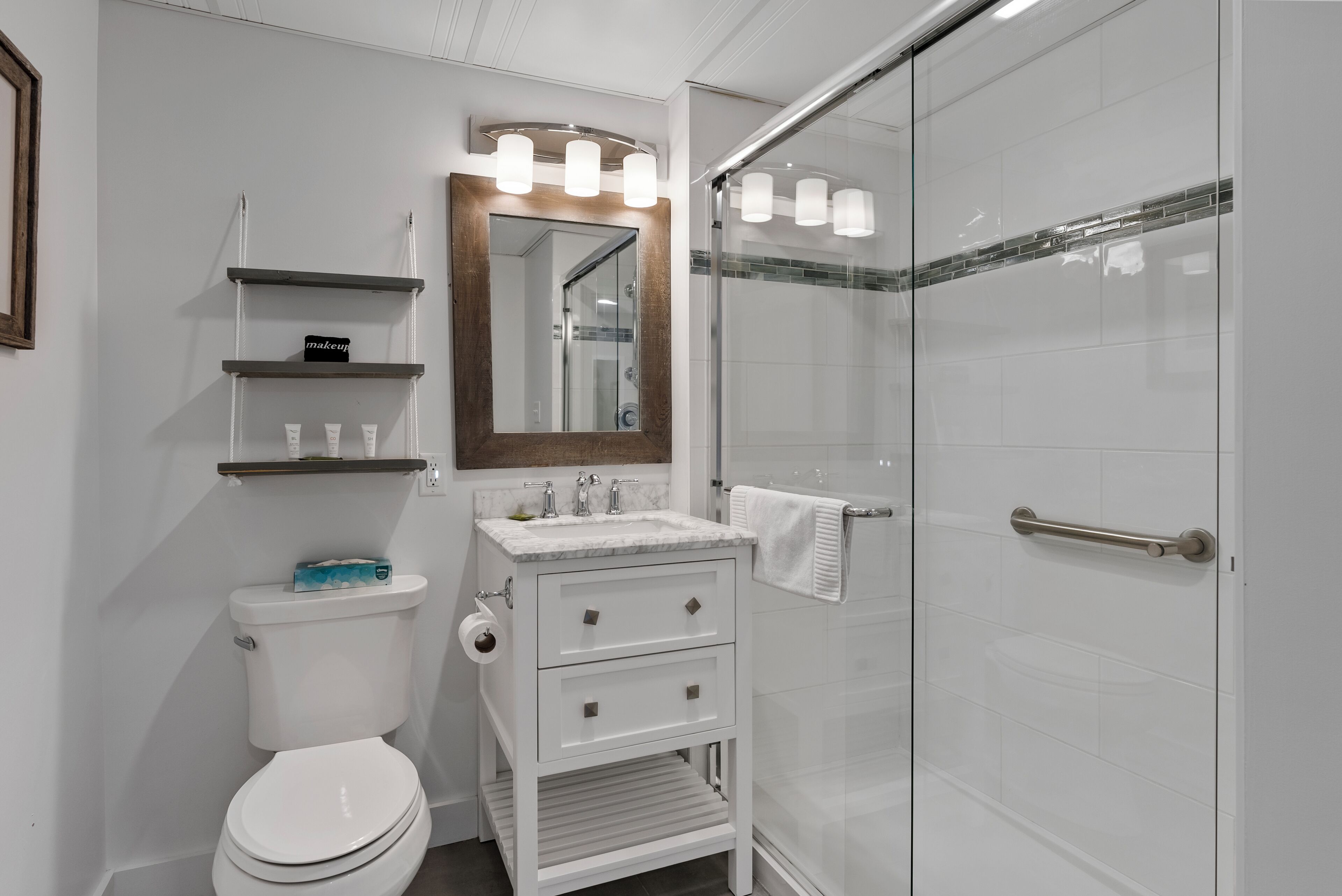 A modern bathroom with a white toilet, a vanity with a mirror, and a glass-enclosed shower.
