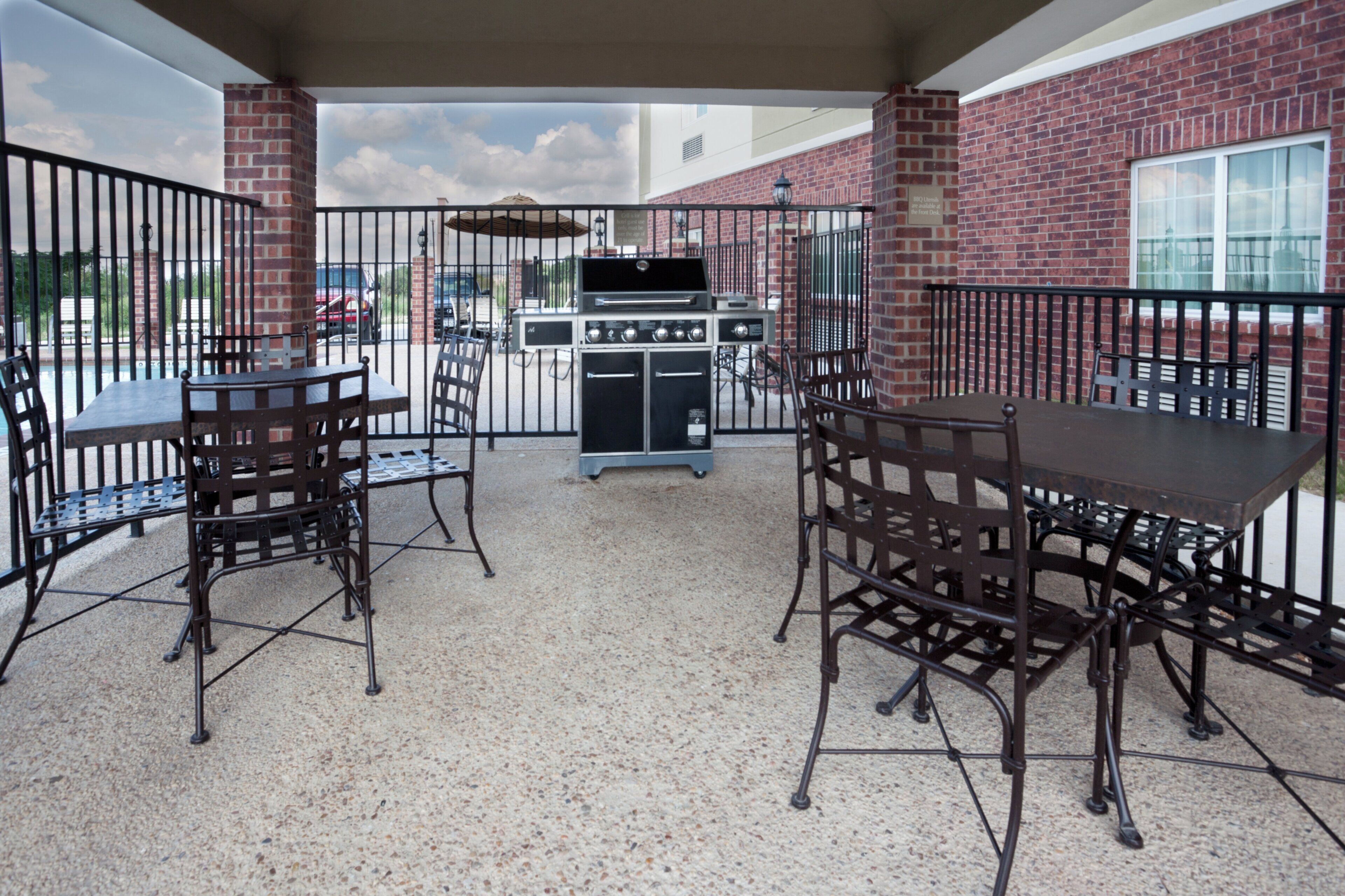 Une terrasse extérieure avec des murs en briques, des rampes en métal et un barbecue.
