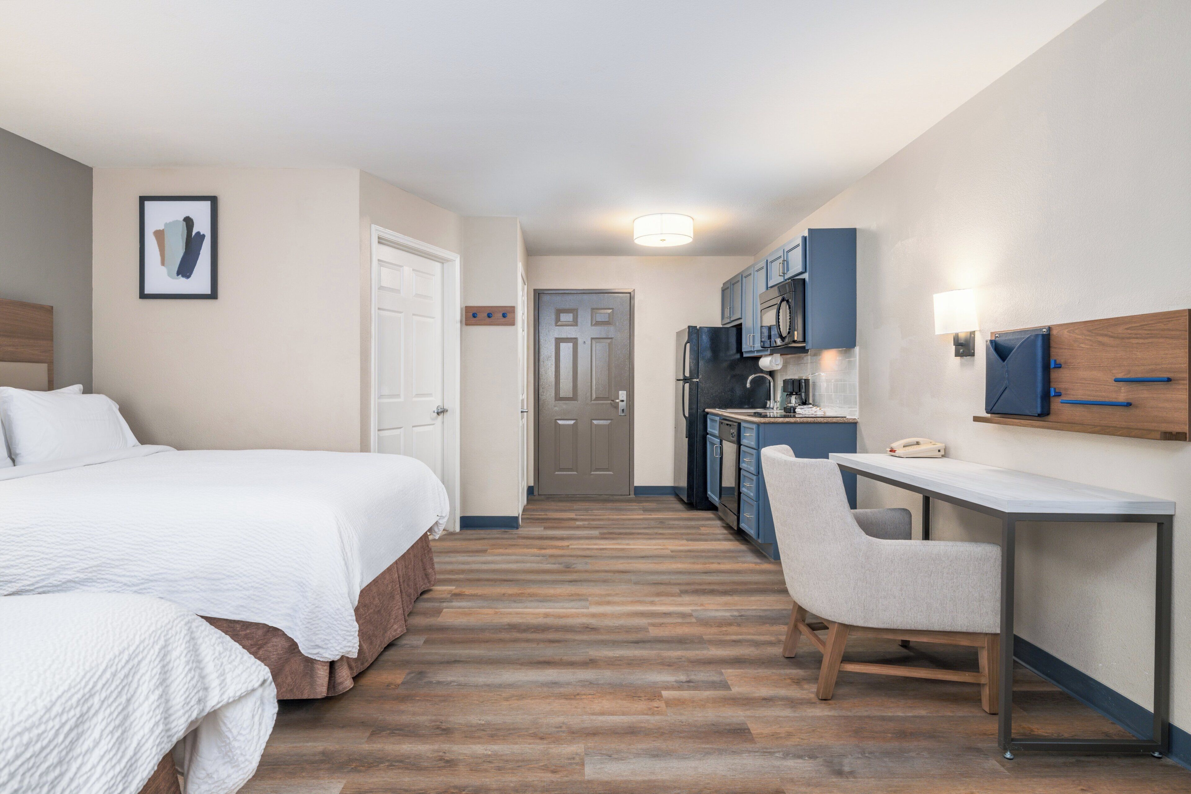 Een hotelkamer met een bed, een bureau en een kitchenette.