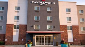 A multi-story hotel with a modern facade, featuring a prominent logo at the top. - Candlewood Suites San Antonio NW Near Seaworld by IHG (San Antonio)