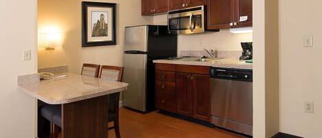 A compact kitchen with a refrigerator, microwave, and dishwasher.