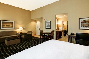Una habitación de hotel con una cama, un escritorio, una silla, un sofá y una mesa de comedor.