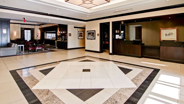 A spacious lobby with a large geometric patterned floor, a reception desk, and a bar area. - Homewood Suites by Hilton Toronto Airport Corporate Centre (Toronto)