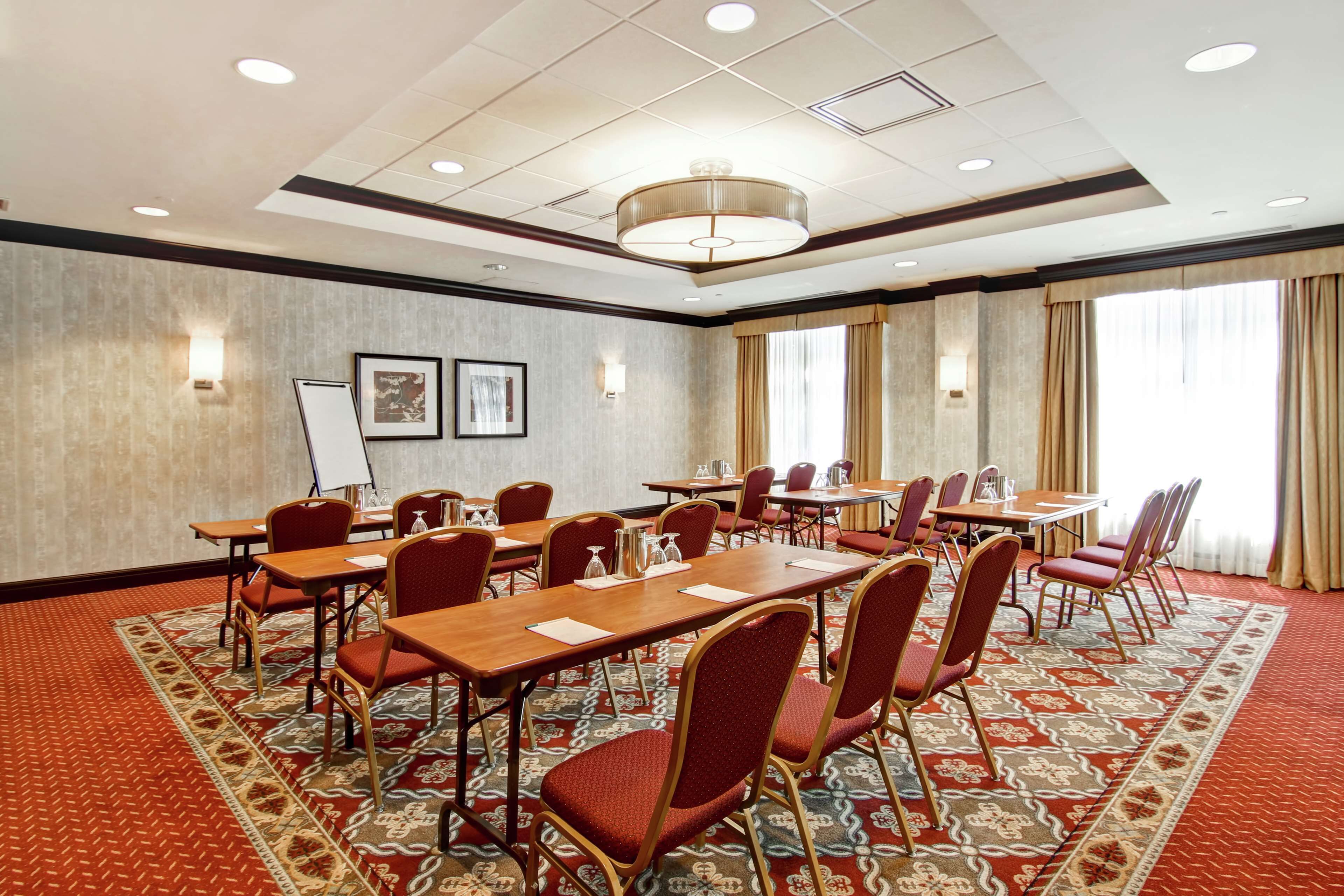 A conference room with tables and chairs, a carpeted floor, and a chandelier.