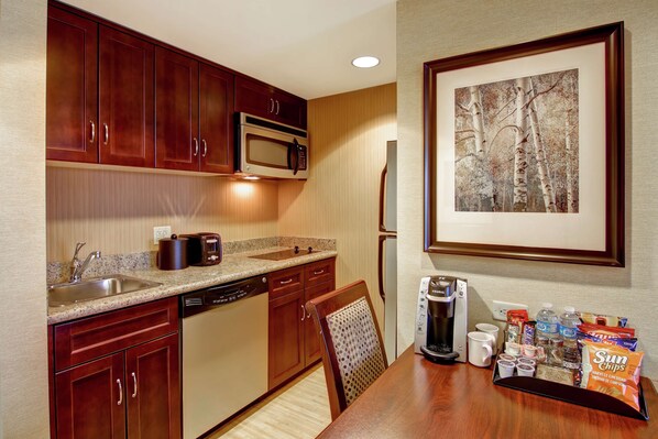A kitchen with wooden cabinets, a microwave, a coffee maker, and a breakfast tray with snacks and beverages.
