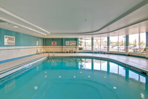 Una piscina con agua cristalina, líneas de profundidad marcadas y señales de seguridad.
