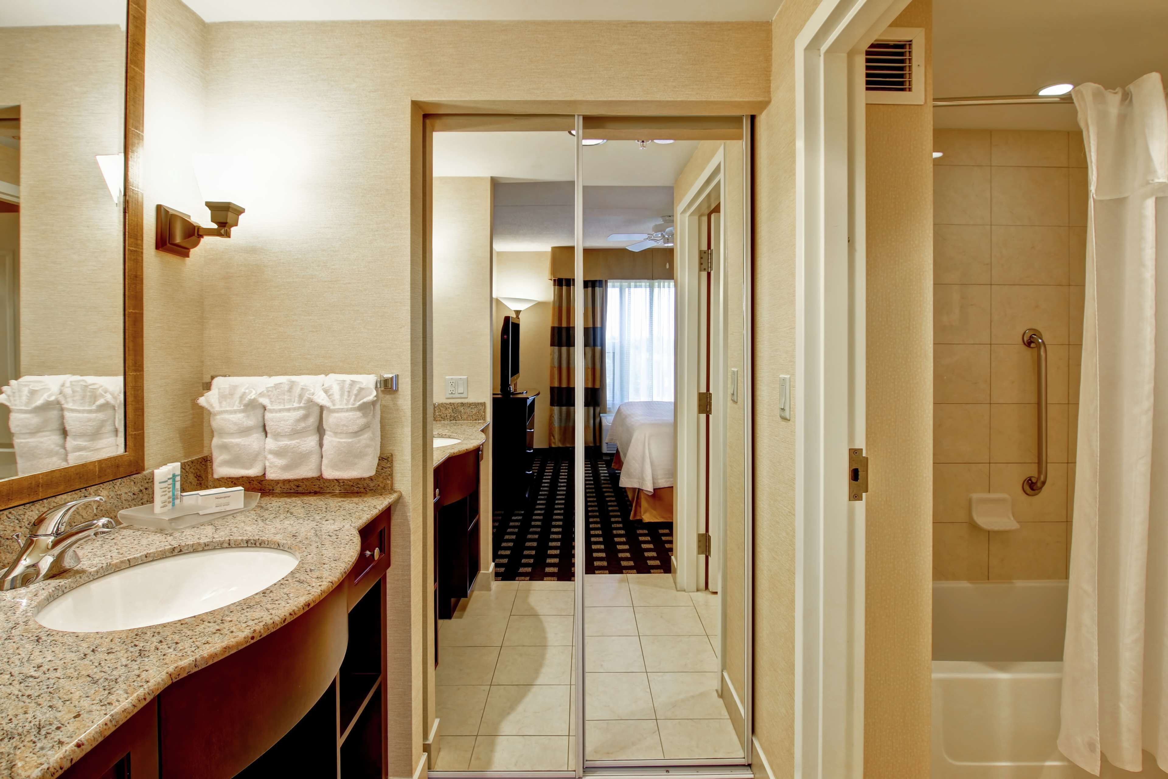 Un baño de hotel con lavabo, espejo y zona de ducha.