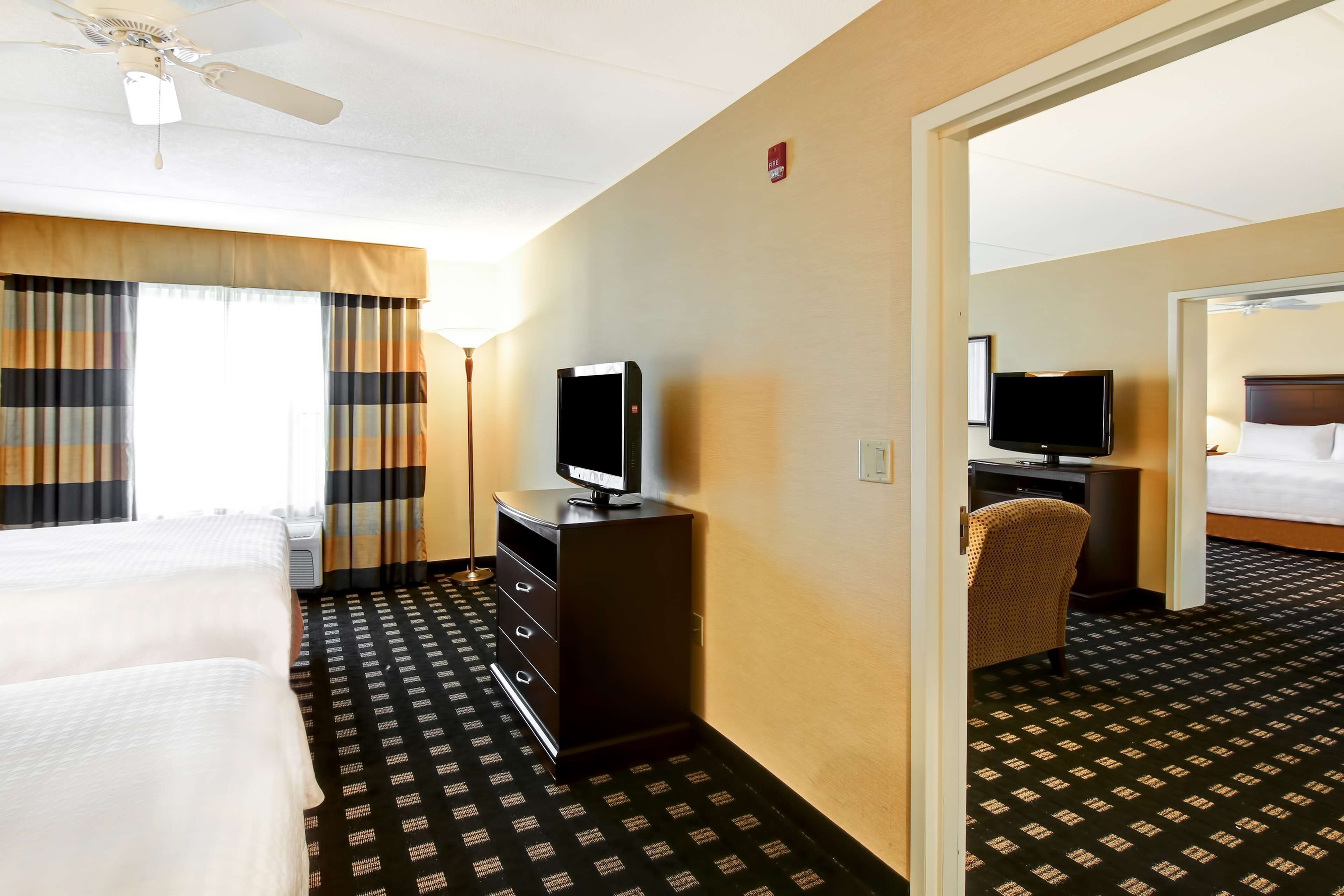 Hotelkamer met een bed, een bureau met televisie, een stoel en een vloerbedekking.