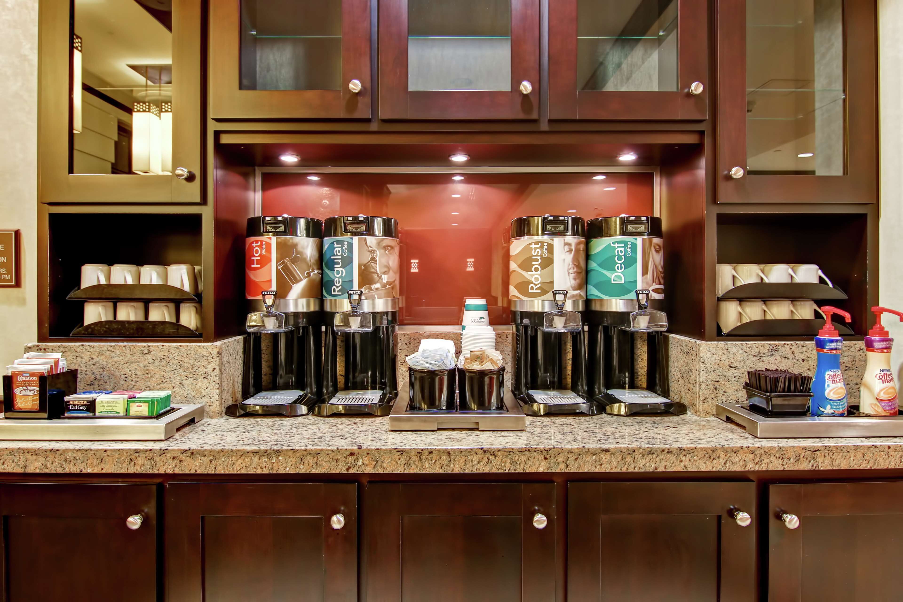 A hotel kitchen with multiple coffee machines, a coffee station, and various coffee-related items.