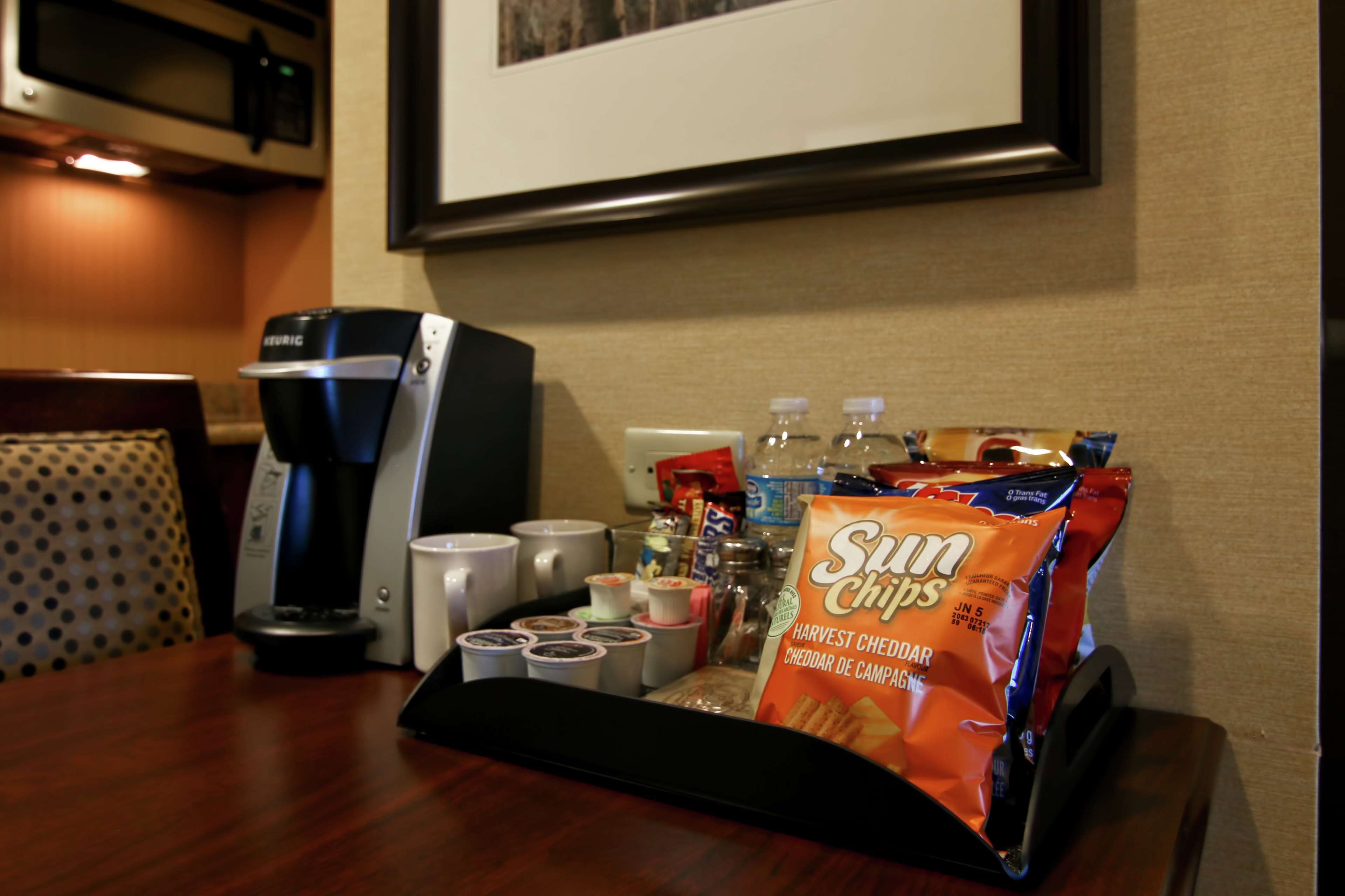 A hotel room with a coffee maker, a tray with snacks, and a bag of Sun Chips.