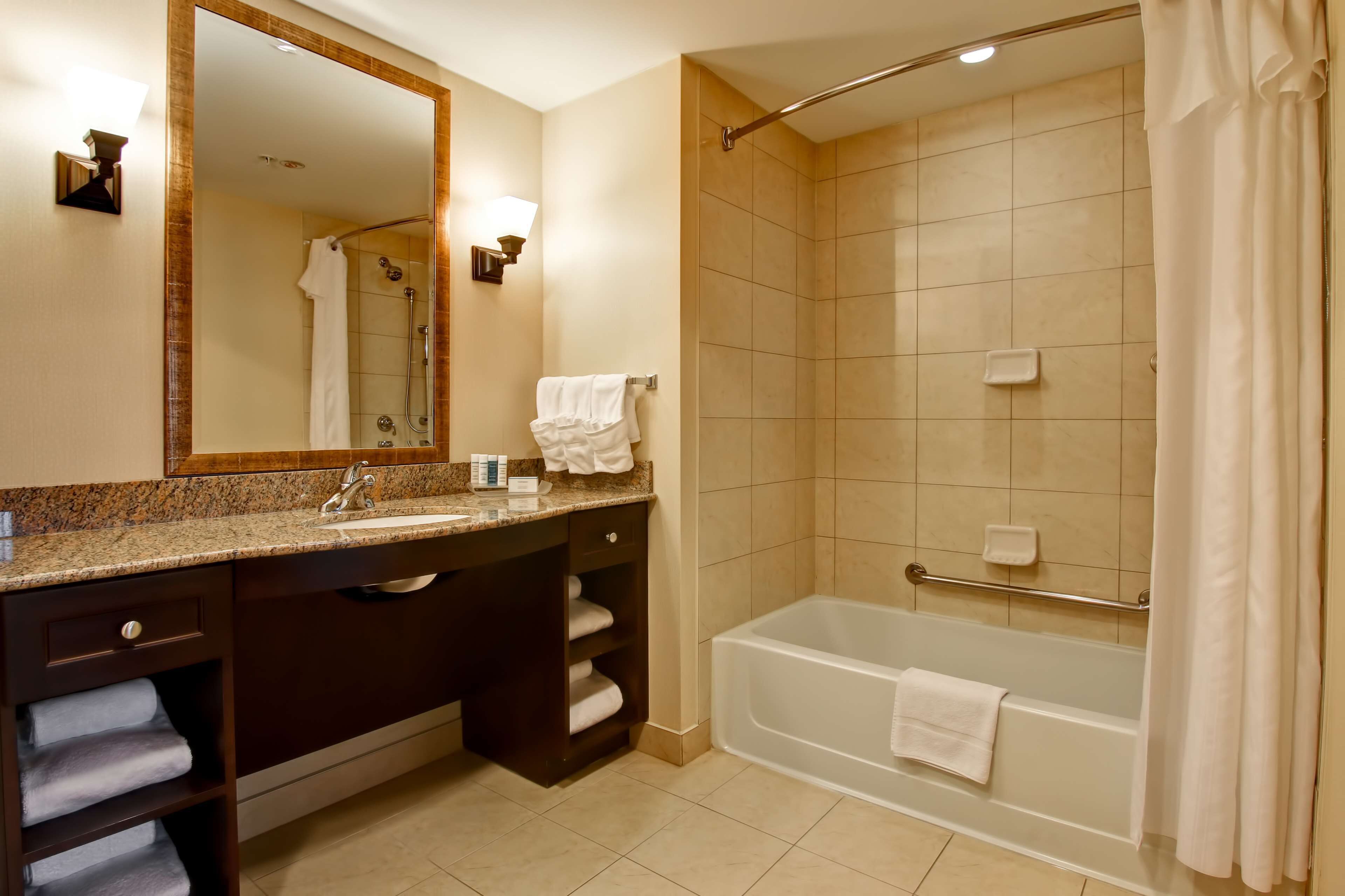 Un baño con lavabo, espejo, tocador, toallero, ducha y bañera.