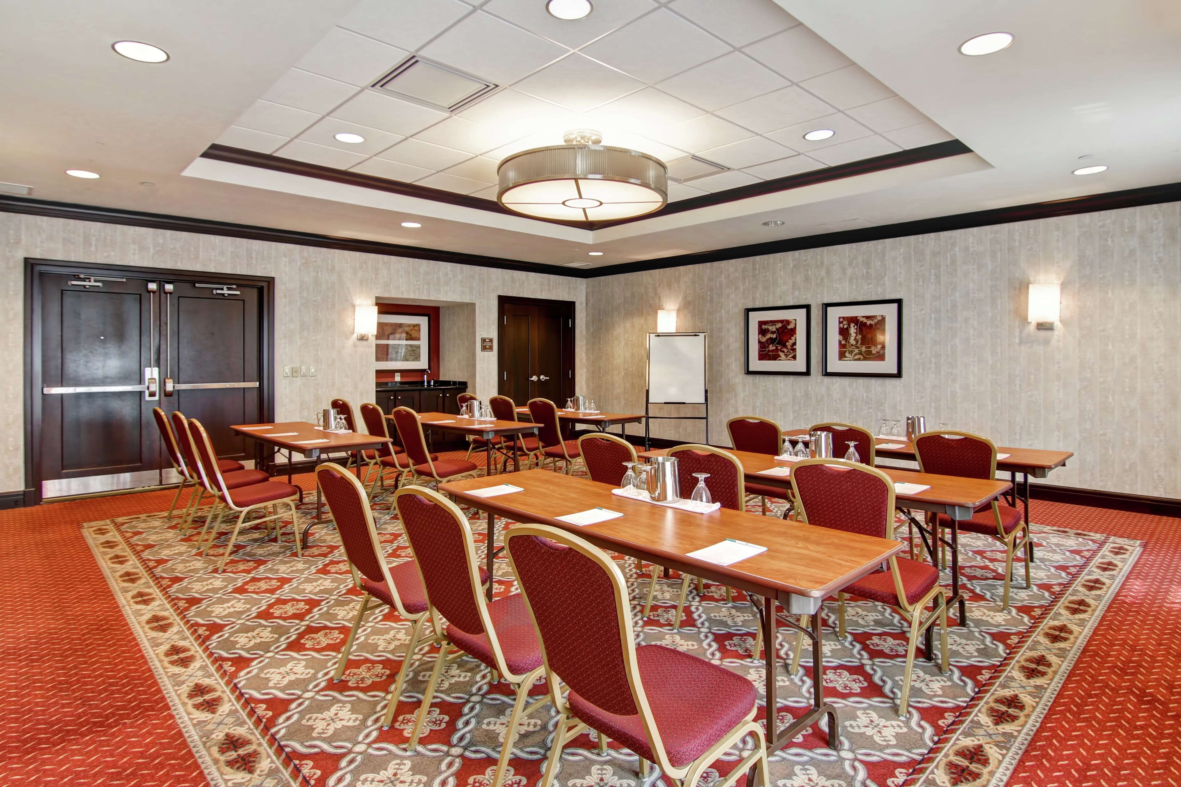 A conference room with multiple tables and chairs, a whiteboard, and framed artwork on the walls.