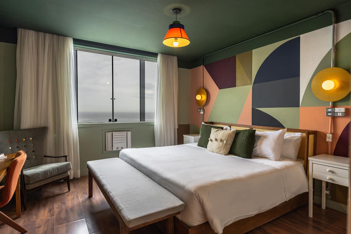 Una habitación de hotel moderna con una cama grande, un escritorio y vistas a la ciudad.
