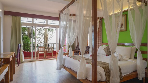 A four-poster bed with white bedding and a green wall behind it. - Tea Valley Resort (Devikolam)