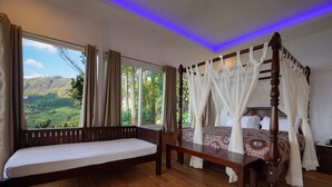 A bedroom with a wooden bed, a daybed, and a large window offering a scenic view. - Tea Valley Resort (Devikolam)