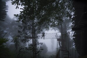 A forested area with a rope bridge and a metal structure.