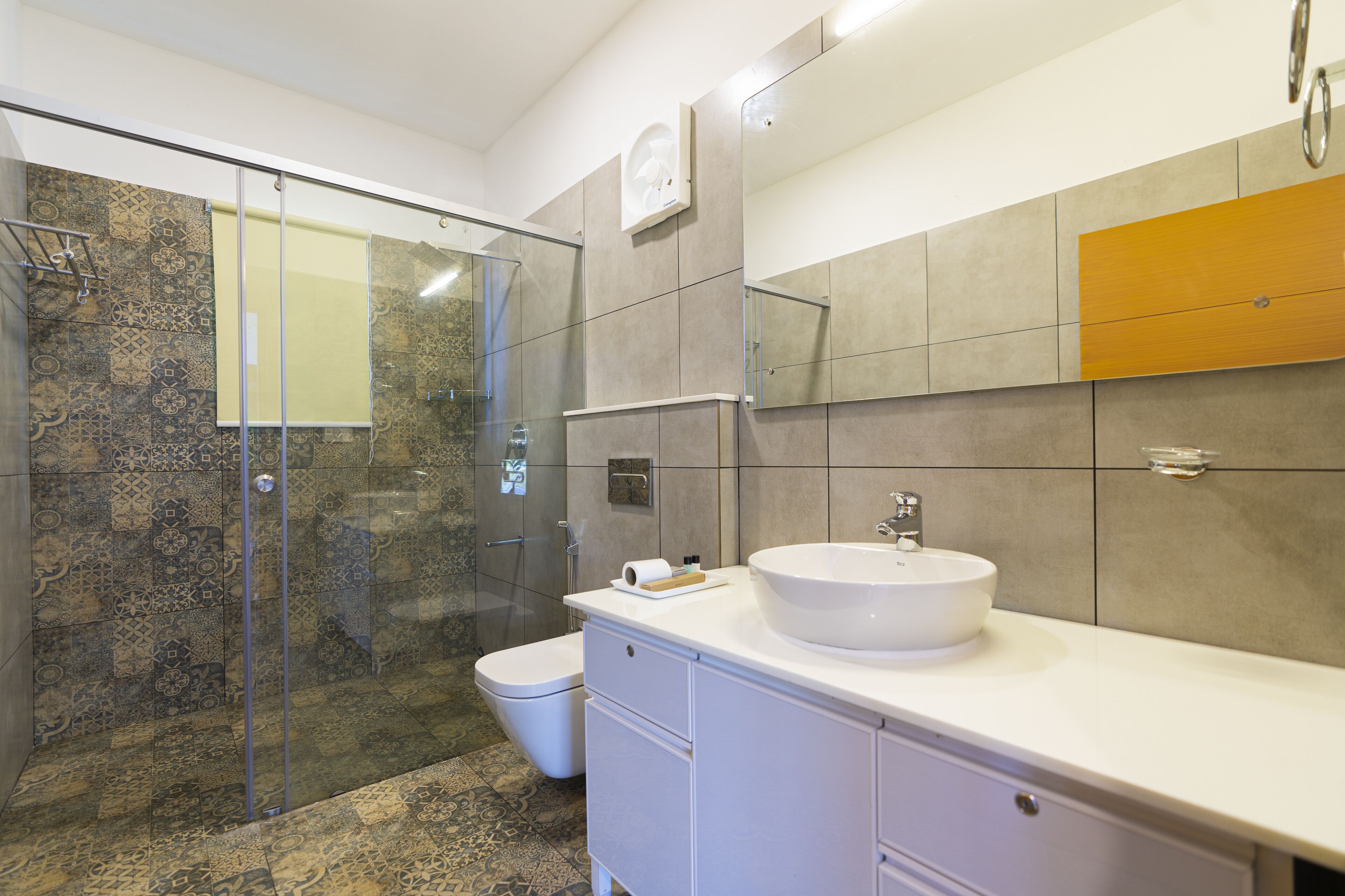 A modern bathroom with a glass-enclosed shower, a white sink, and a toilet.