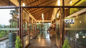 A hotel entrance with glass doors, a covered walkway, and potted plants. - Tea Valley Resort (Devikolam)
